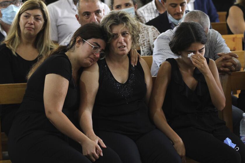 The mother, center, and two sisters of Nicole al-Helou, who was killed by the explosion Tuesday that hit the seaport of Beirut, mourn during her funeral, in Sarba village, southern Lebanon, Thursday, Aug. 6, 2020. French President Emmanuel Macron said an independent, transparent investigation into the massive explosion in Beirut is "owed to the victims and their families" by Lebanese authorities. During Macron's visit to the city on Thursday, angry crowds approached him and the Beirut governor as they walked through a blast-torn street. (AP Photo/Mohammed Zaatari)