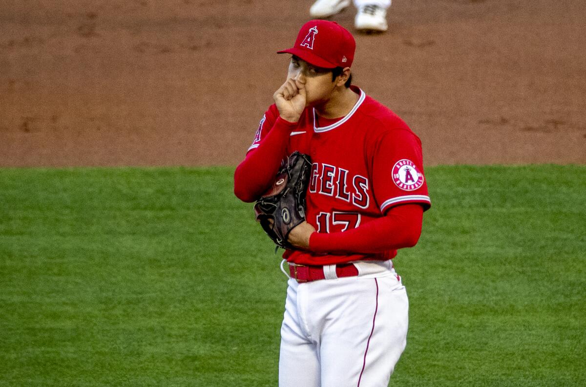 Angels pitcher Shohei Ohtani blows on his hand after walking a third Texas Rangers batter.