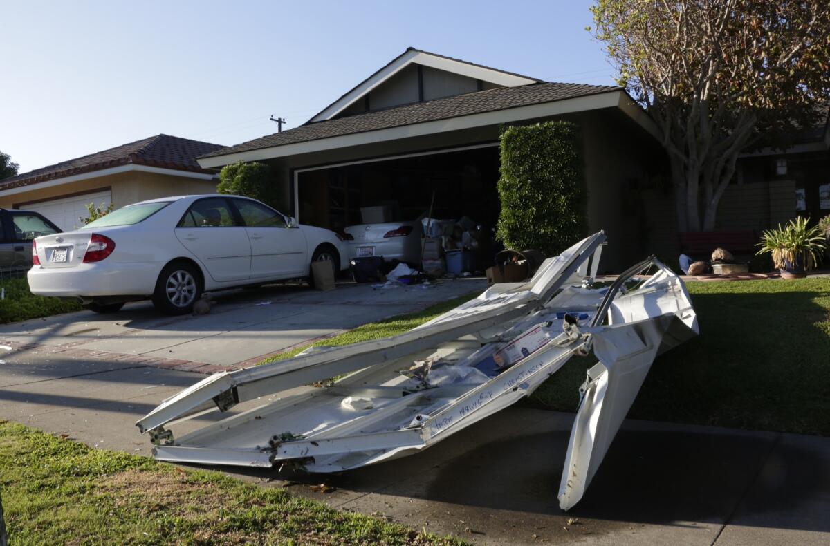 A mangled piece of an overhead door blown out in an explosion in a garage at a home in Orange lies in the front yard of the residence. A 47-year-old man was killed.