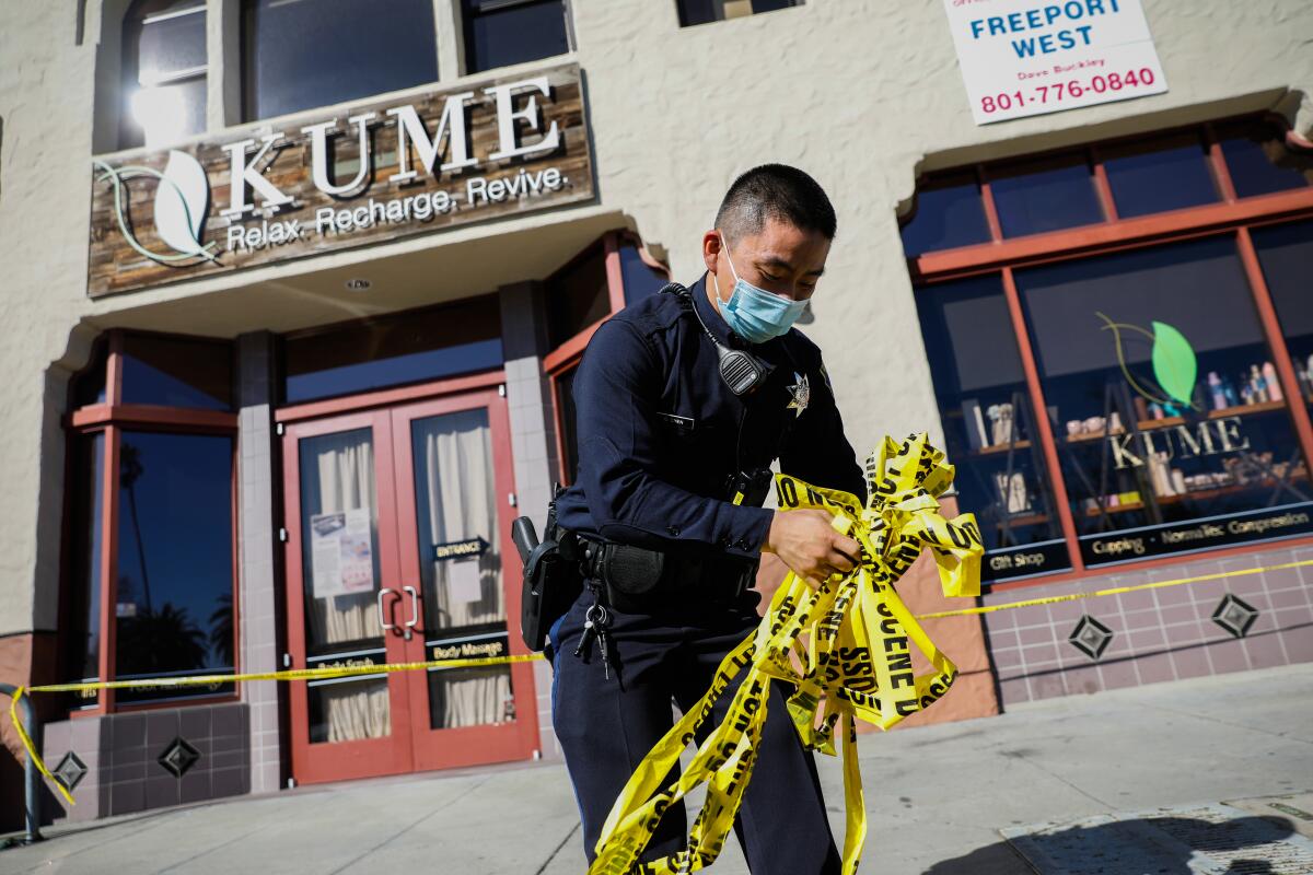 A police officer collects caution tape outside the scene of a shooting in Oakland.