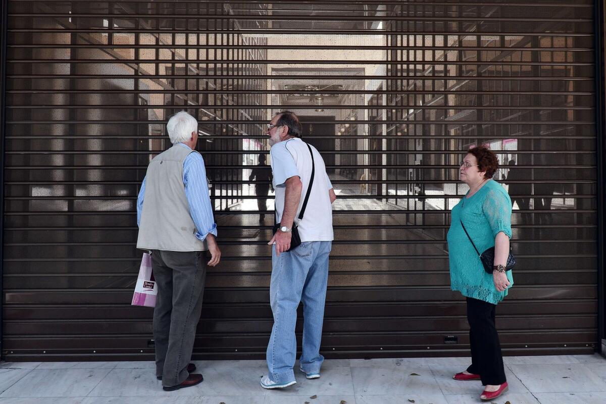 Pensioners stand behind shutters of the Alpha Bank headquarters in central Athens on June 29.