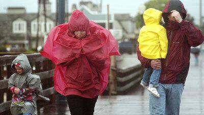 Arseniy Kalistratoe, 6, left, his mother, Julia, his sister, Uliana, 2, and his father, Andre, stroll in their rain gear on the Seal Beach Pier.