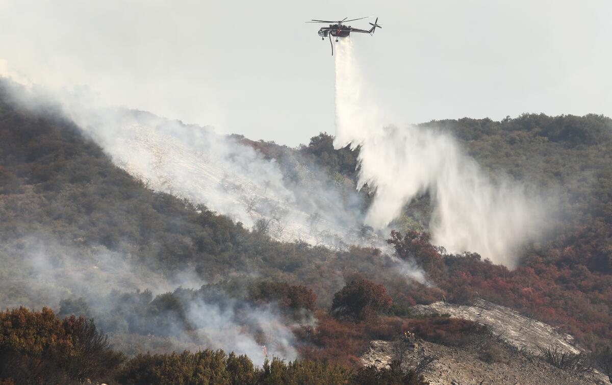 A helicopter makes a water drop on a fire.