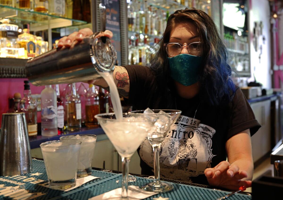 Bartender Taylor Osorio wears a face mask as she pours drinks at Centro Cocina Mexicana restaurant in Sacramento on Friday. A state rule change will make it easier for bars and wineries to sell to-go drinks.