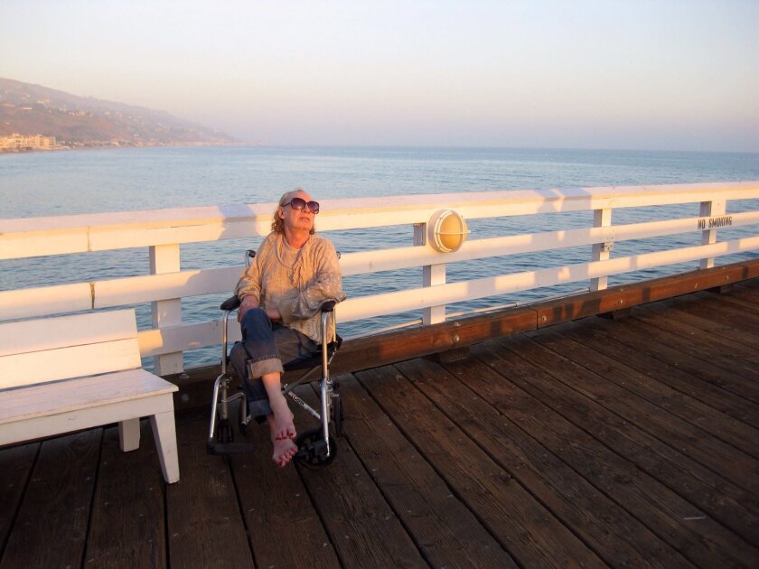 In this 2012 photo provided by David Chick, actress Holly Woodlawn sits on Fisherman's Pier in Malibu.