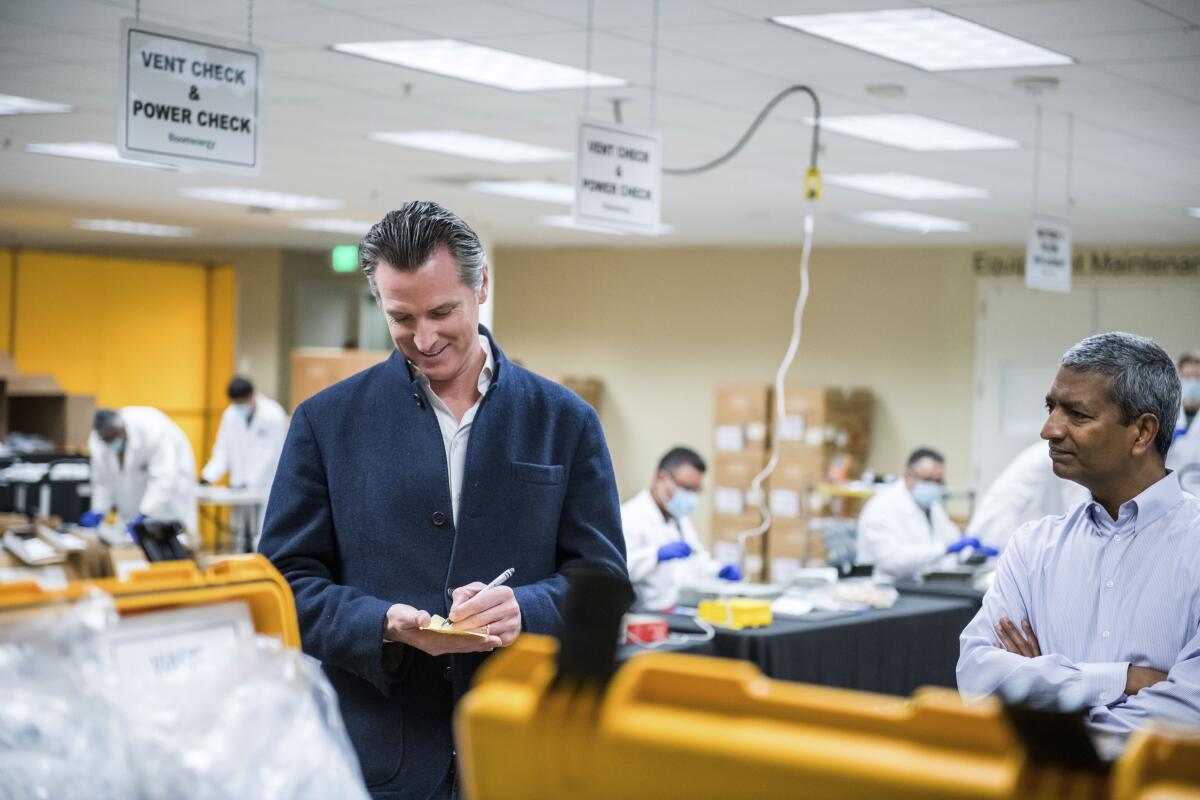 California Gov. Gavin Newsom writes down a note during a tour with Sridhar of the Bloom Energy Sunnyvale, Calif. on March 28.