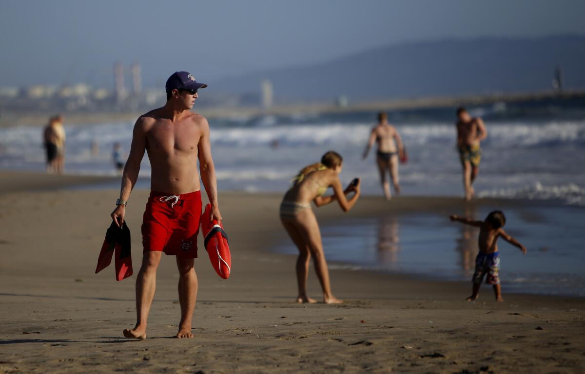 Lifeguard Morgan Wallace watches the water in Venice in this 2014 photo. Lifeguards are warning that strong surf and warm temperatures could mean greater hazards for swimmers and surfers over Labor Day weekend.