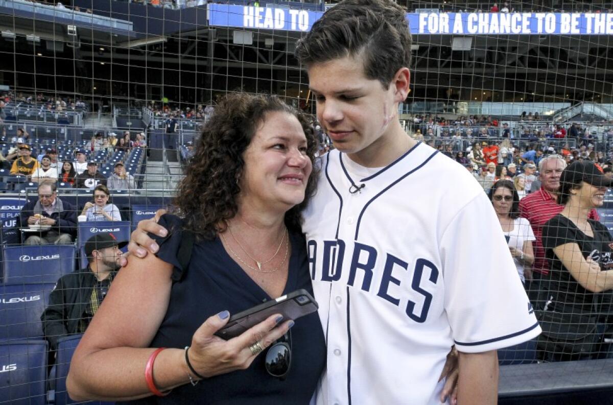 Keane Webre-Hayes, 14, who was attacked by a great white shark last year, hugs his mother Ellie Hayes after he threw the ceremonial first pitch prior to the start of the Padres game against the Giants at Petco Park on Tuesday, July 2, 2019.