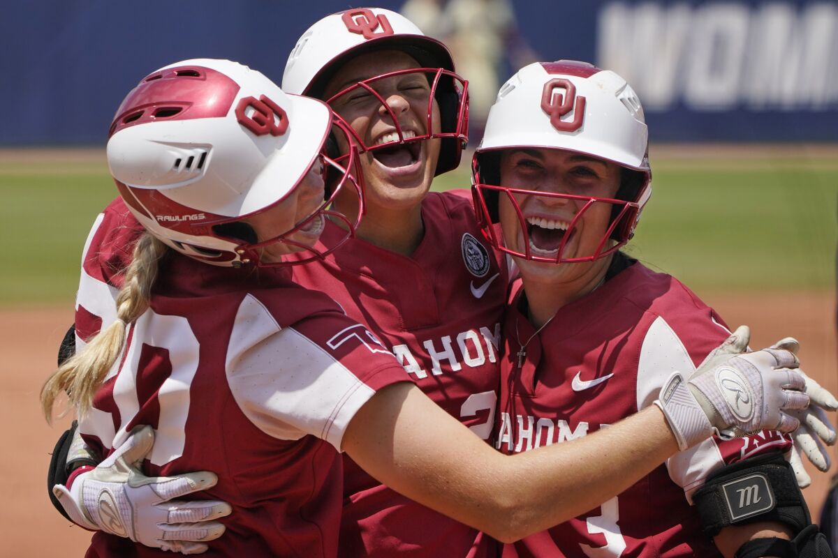Oklahoma's Jayda Coleman, center, celebrates at home plate with teammates Jana Johns, left, and Grace Lyons, right, following her home run against Florida State in the second inning of the final game of the NCAA Women's College World Series softball championship series Thursday, June 10, 2021, in Oklahoma City. (AP Photo/Sue Ogrocki)