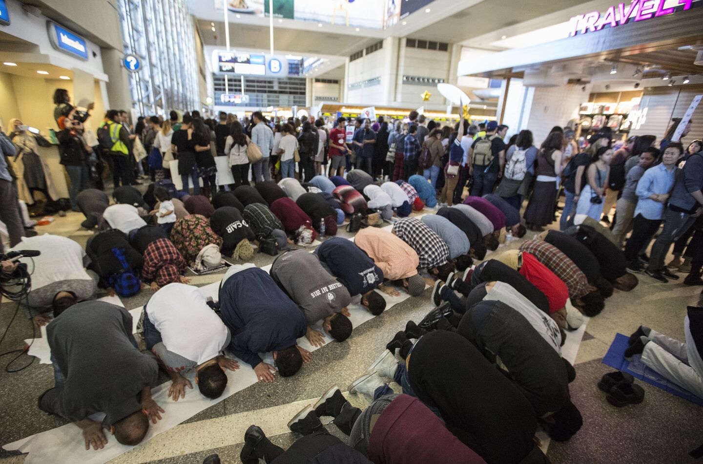 Muslims pray as hundreds stand in support on the departure level of the Tom Bradley International Terminal during a protest against President Trump's immigration order.