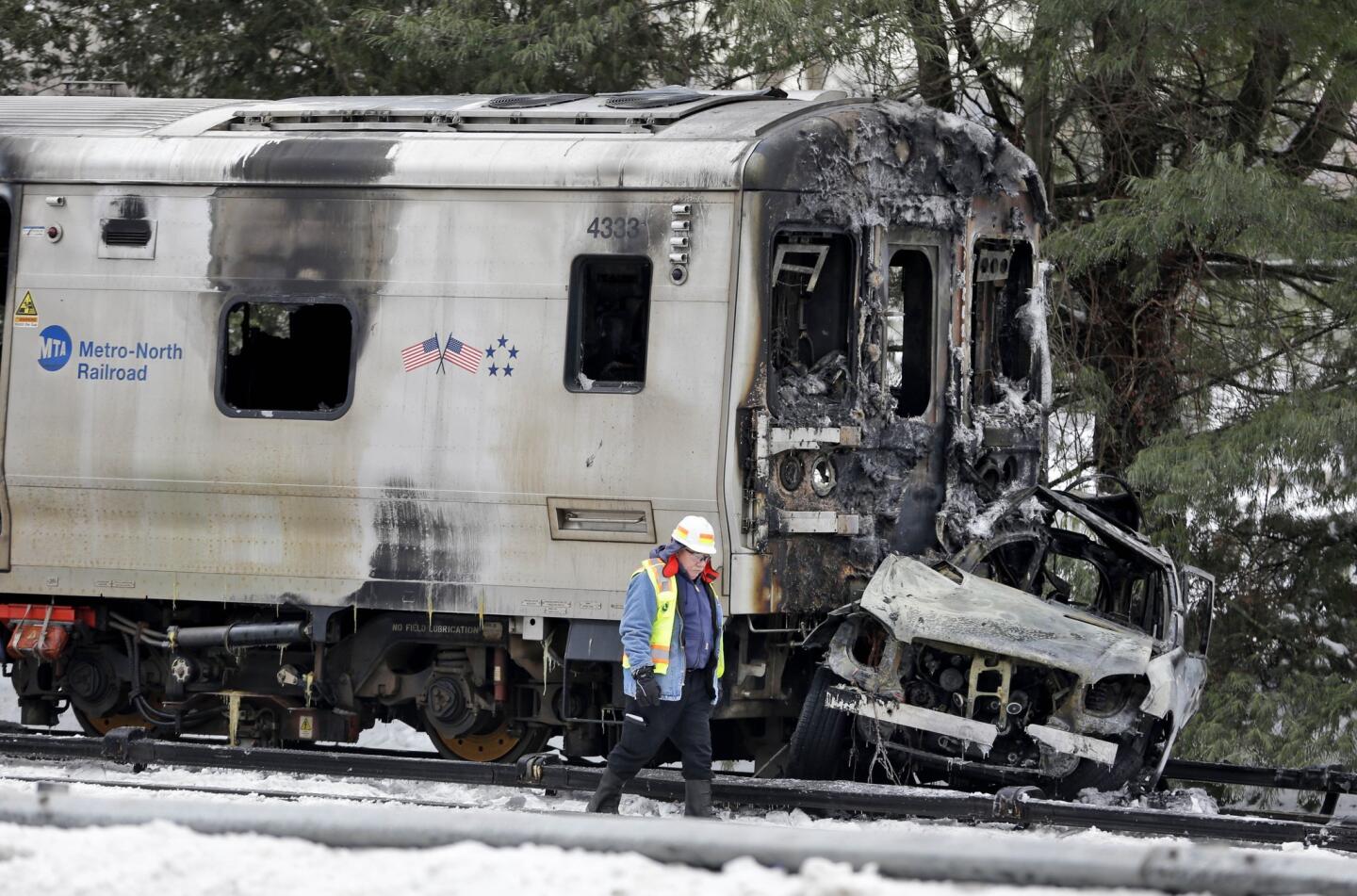 A man wearing a Federal Railroad Administration vest looks over the wreckage of a Metro-North Railroad train and an SUV in Valhalla, N.Y.