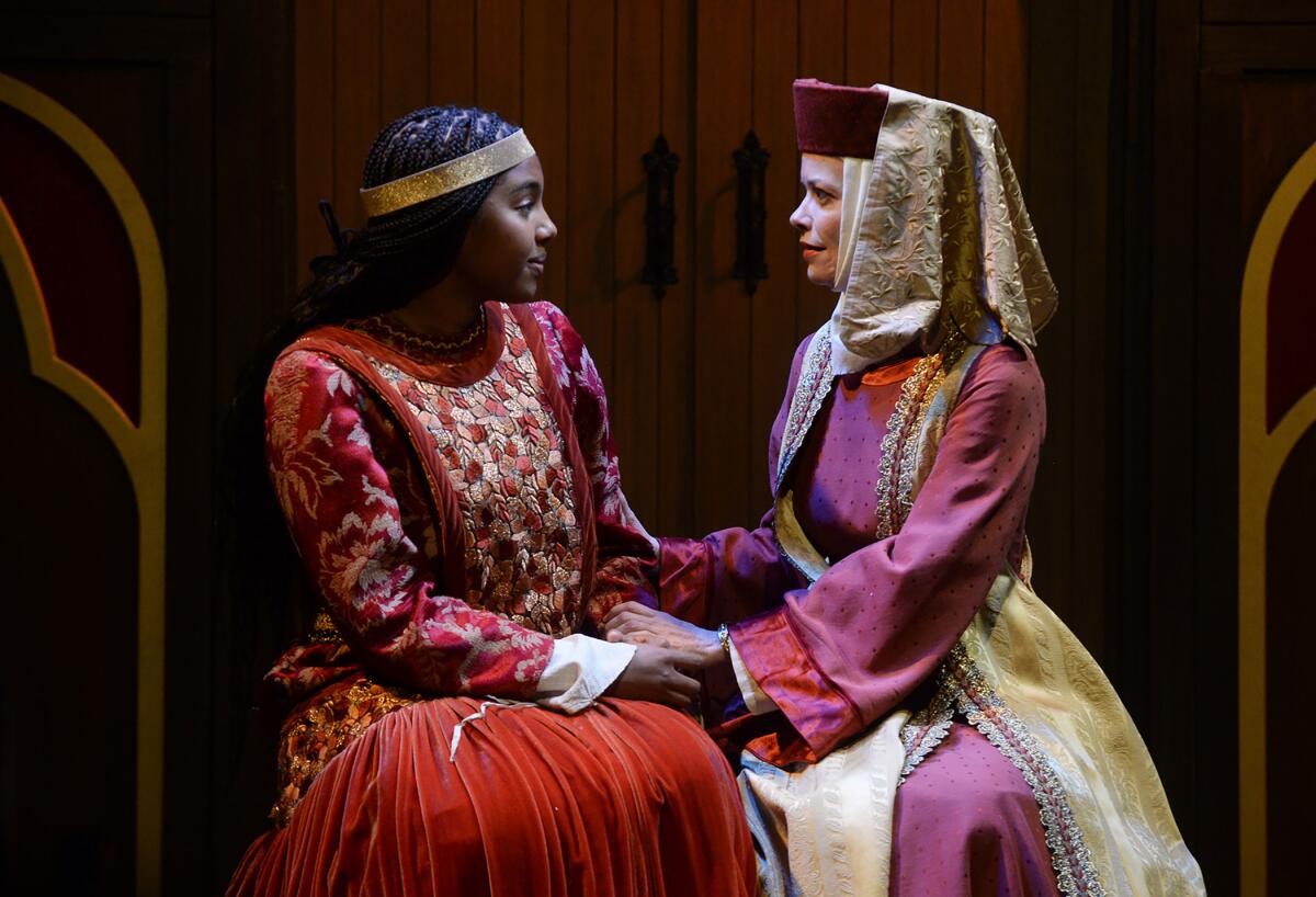 Two women in Renaissance clothing sit and face each other 