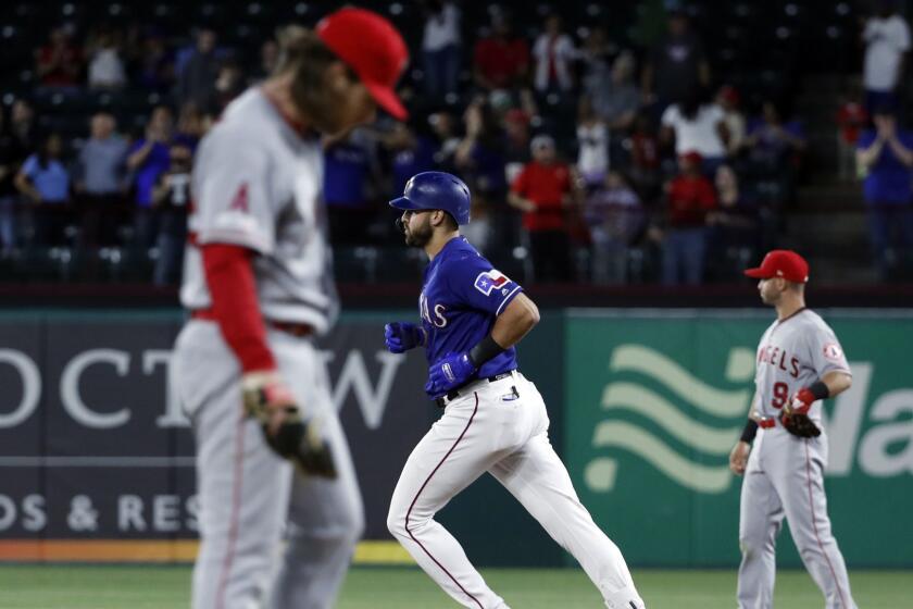 Los Angeles Angels relief pitcher Dillon Peters, left, stands on the mound and second baseman Tommy La Stella looks to the outfield as Texas Rangers' Joey Gallo rounds the bases on his two-run home run during the sixth inning of a baseball game in Arlington, Texas, Tuesday, April 16, 2019. (AP Photo/Tony Gutierrez)