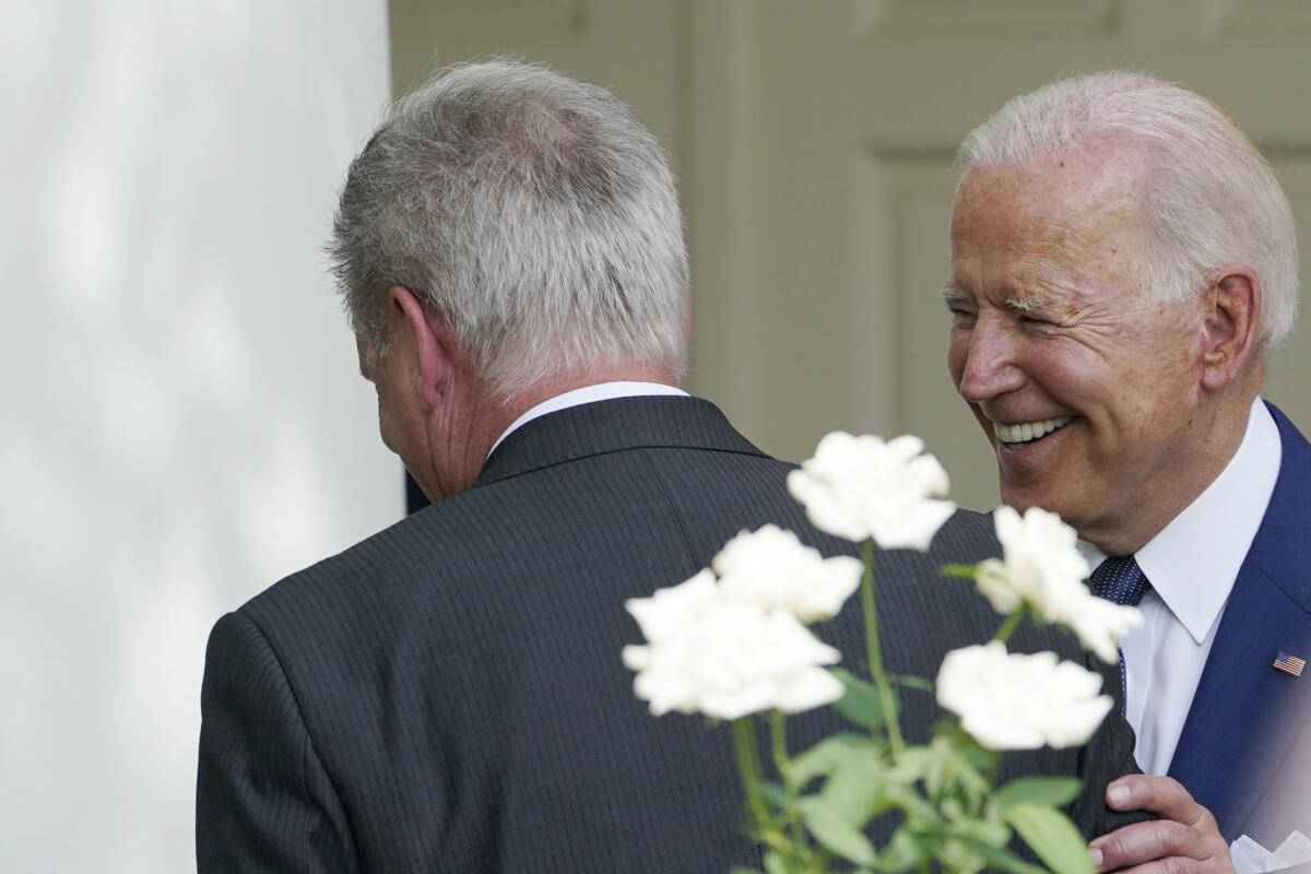 President Biden smiling as he stands with a hand on Kevin McCarthy's arm.