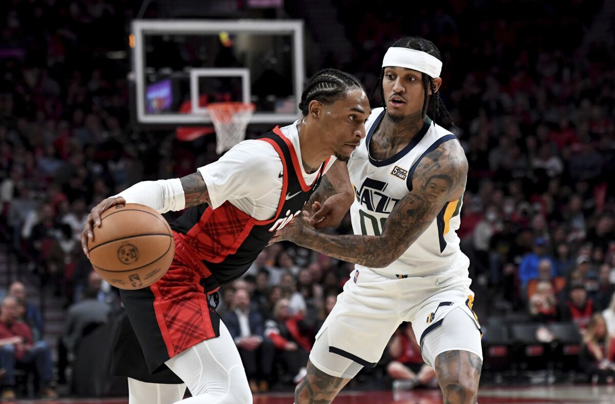 Portland Trail Blazers guard Keon Johnson, left, drives to the basket on Utah Jazz guard Jordan Clarkson, right, during the first half of an NBA basketball game in Portland, Ore., Sunday, April 10, 2022. (AP Photo/Steve Dykes)