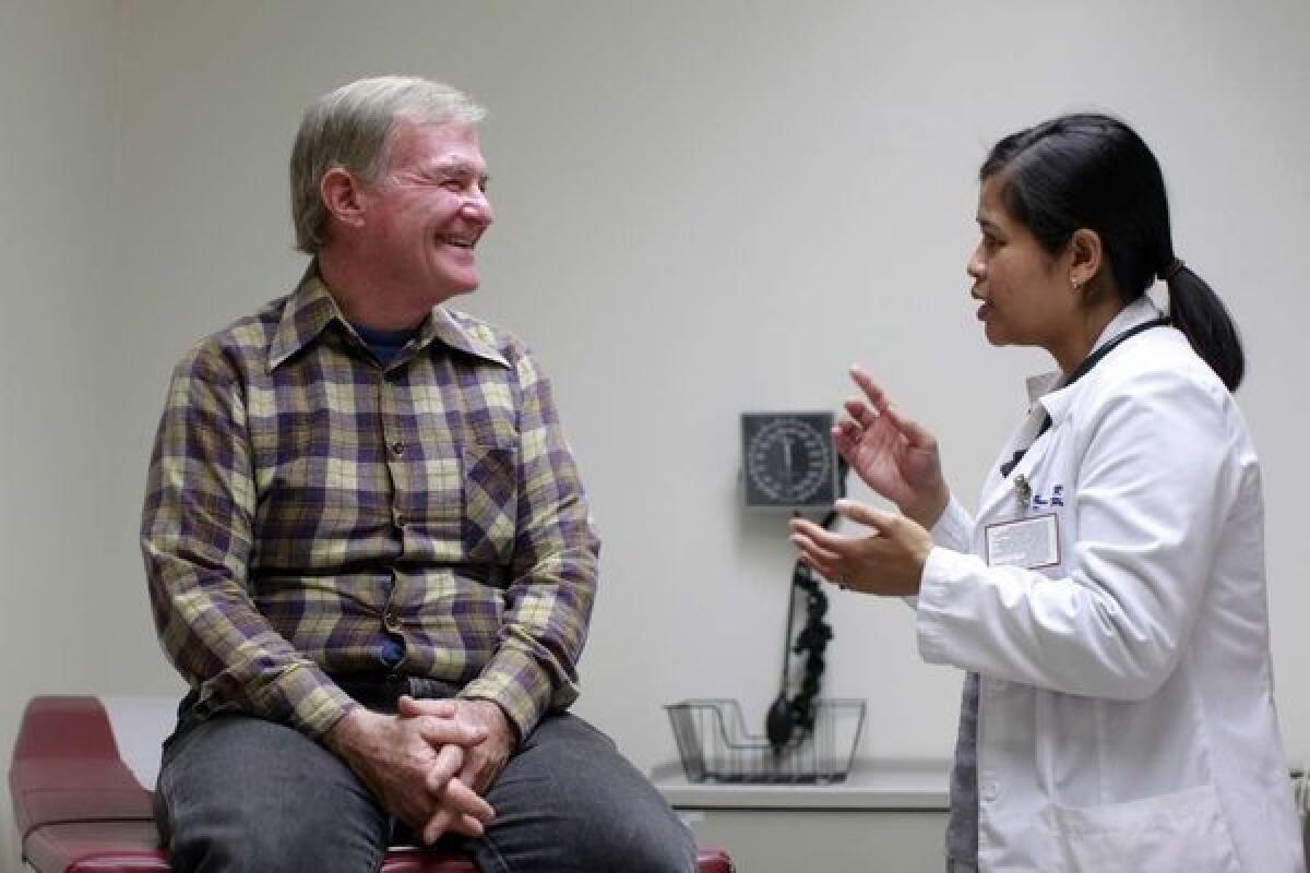 Nurse practitioner Savinh Pouv talks with patient Jeffrey Grimes in 2011. Researchers are studying how patient involvement in decision-making might influence costs.