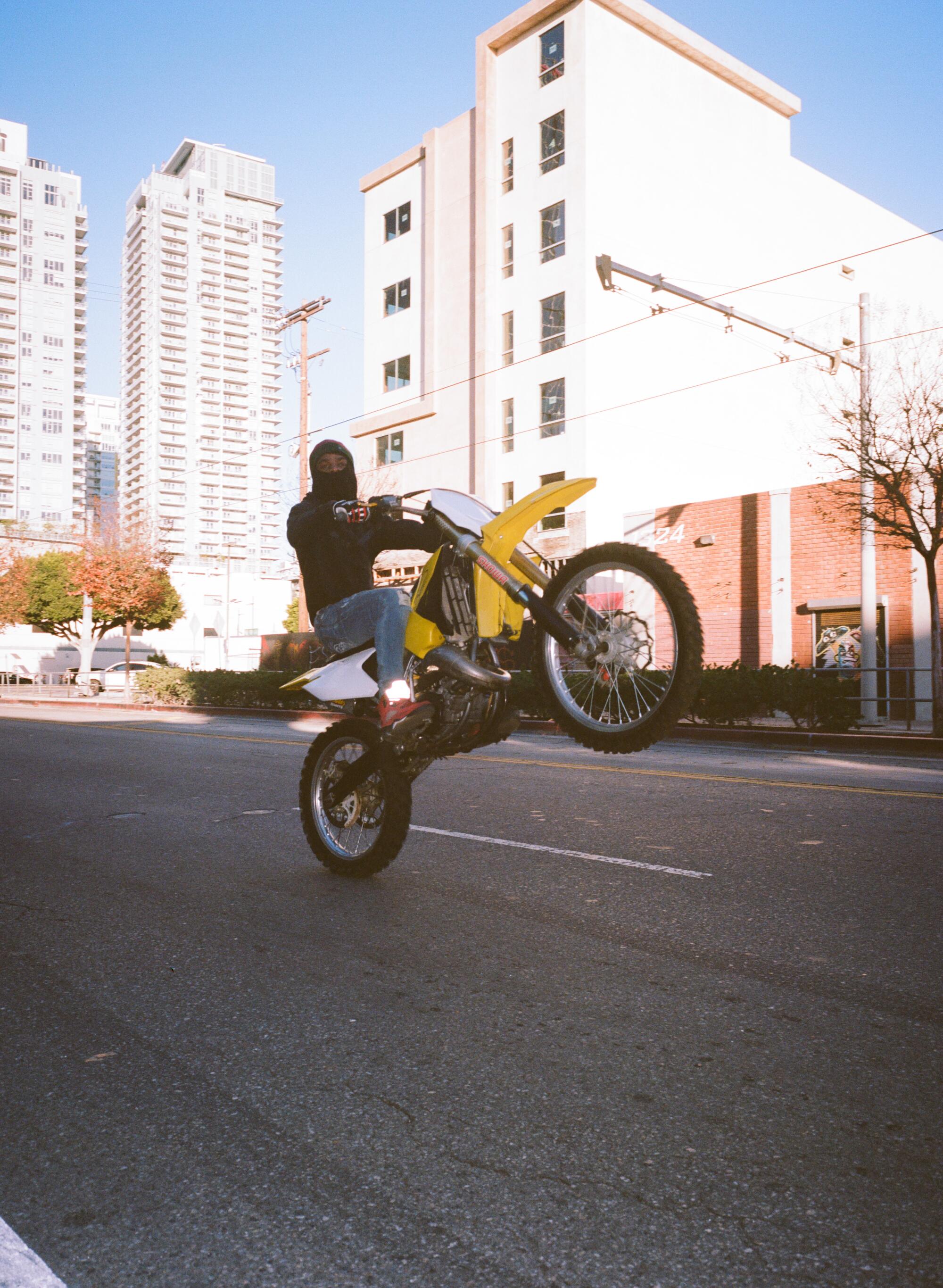 A rider pops a wheelie on a city street