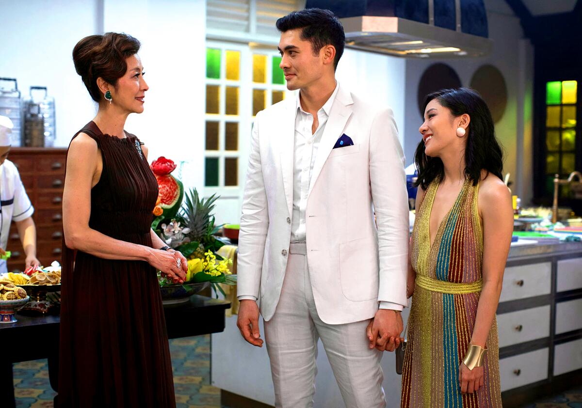 An Asian mom, son and prospective daughter-in-law stand talking in the movie "Crazy Rich Asians" 
