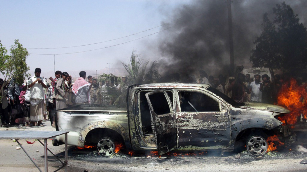 Bystanders watch the car of Yemeni intelligence officer Mohammed al-Saidi burn after he was killed by a suicide bomber in the southern city of Ataq.