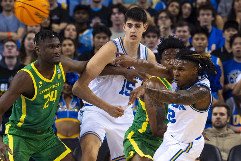 UCLA guard Dylan Andrews, right, passes in front of Oregon's Mahamadou Diawara and UCLA's Aday Mara.