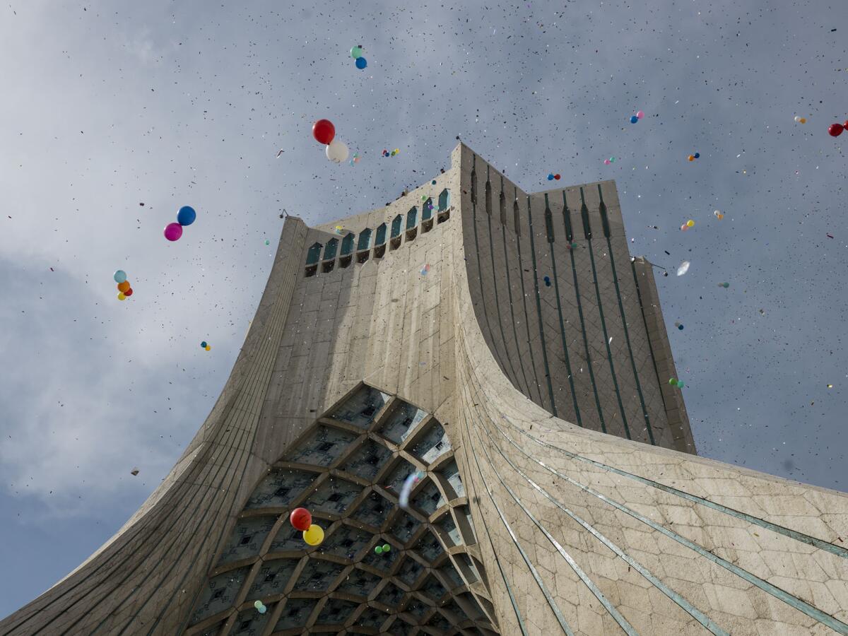 Against the backdrop of a massive tower, balloons float skyward in "Iran, Freedom Sq.," a 2015 work by Newsha Tavakolian.