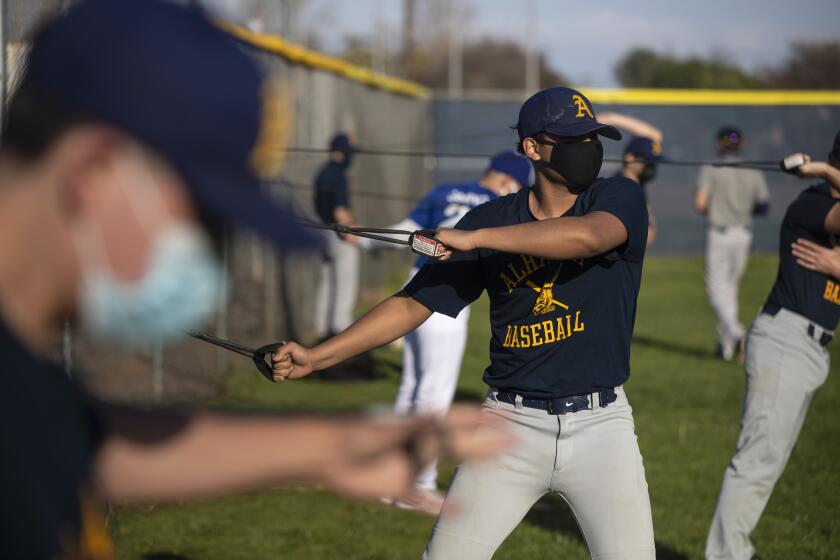 SAN GABRIEL, CA - MARCH 09: Alhambra High School junior Justin Flores stretches with resistance bands as he and teammates warm up for the first baseball practice since the pandemic began on Tuesday, March 9, 2021 in San Gabriel, CA. (Brian van der Brug / Los Angeles Times)