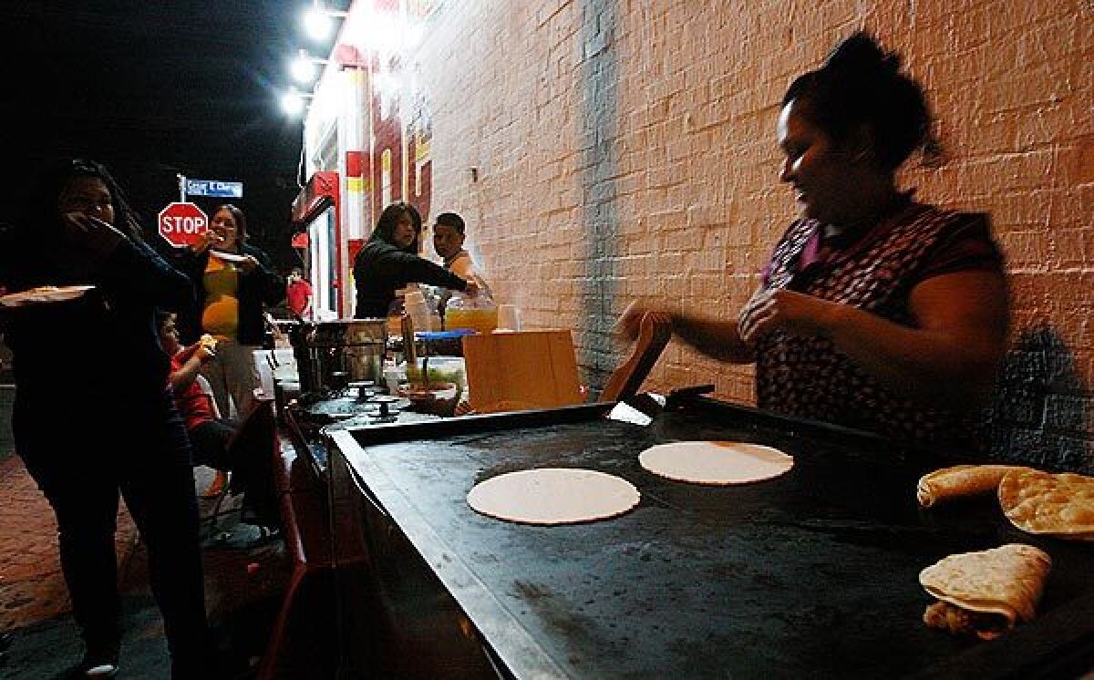 A woman heats tortillas at a sidewalk food stall along Cesar Chavez Avenue in Boyle Heights. Food vendors who gather illegally in the area recently showed up at Los Angeles City Hall to complain that they have become the target of a police effort to clean up the neighborhood.