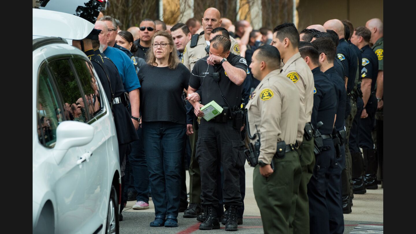 The body of a slain Whittier police officer is escorted from UC Irvine Medical Center to a van to be driven to the coroners.