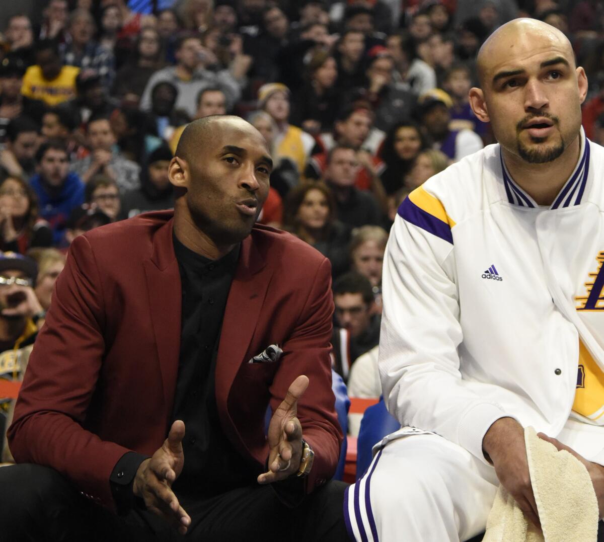 Lakers guard Kobe Bryant, sitting out his second consecutive game because of soreness, chats with center Robert Sacre in the first half.