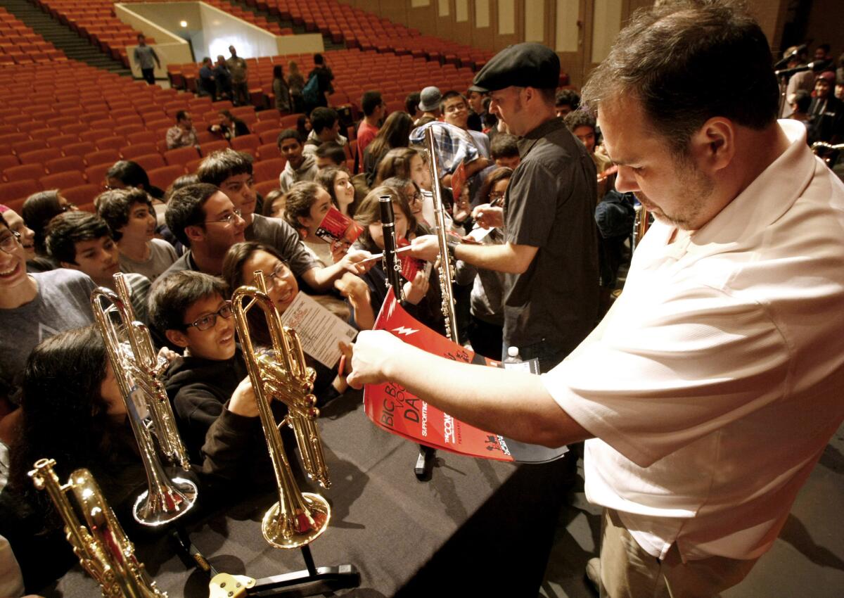 Members of the Big Bad Voodoo Daddy horn section Glen Marhevka, center, of Glendale, and Anthony Bonsera, right, sign autographs for local high school and junior high students after giving a clinic on playing music, at Glendale High School on Tuesday, Feb. 18, 2014. The band will perform a fundraising concert at the Alex Theater in a few days to benefit music and arts at Glendale schools.