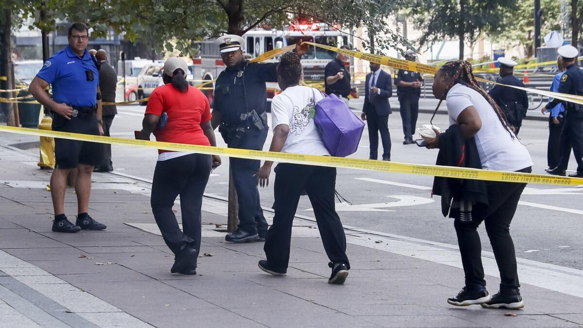 Pedestrians duck under police tape at the scene of a shooting in Cincinnati on Thursday.