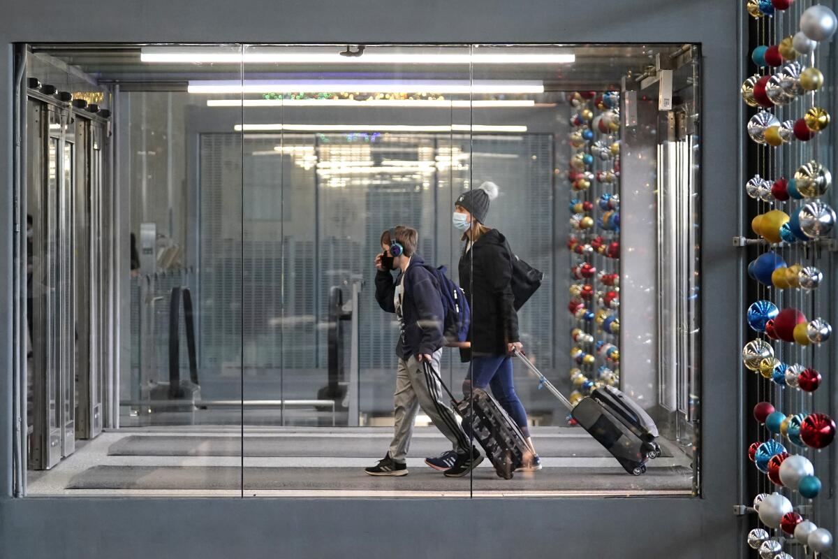 En esta fotografía del domingo 29 de noviembre de 2020 unas personas caminan en la Terminal 3 