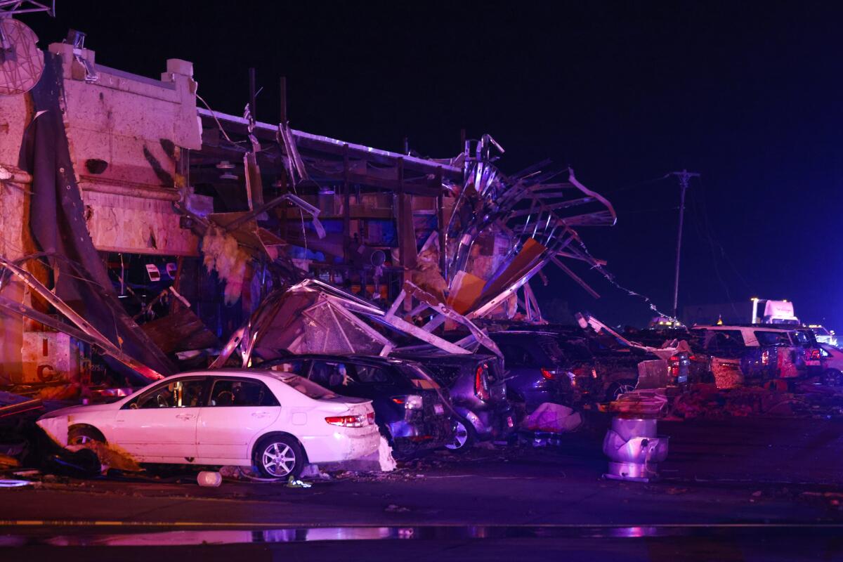 Cars outside a damaged gas station at night.