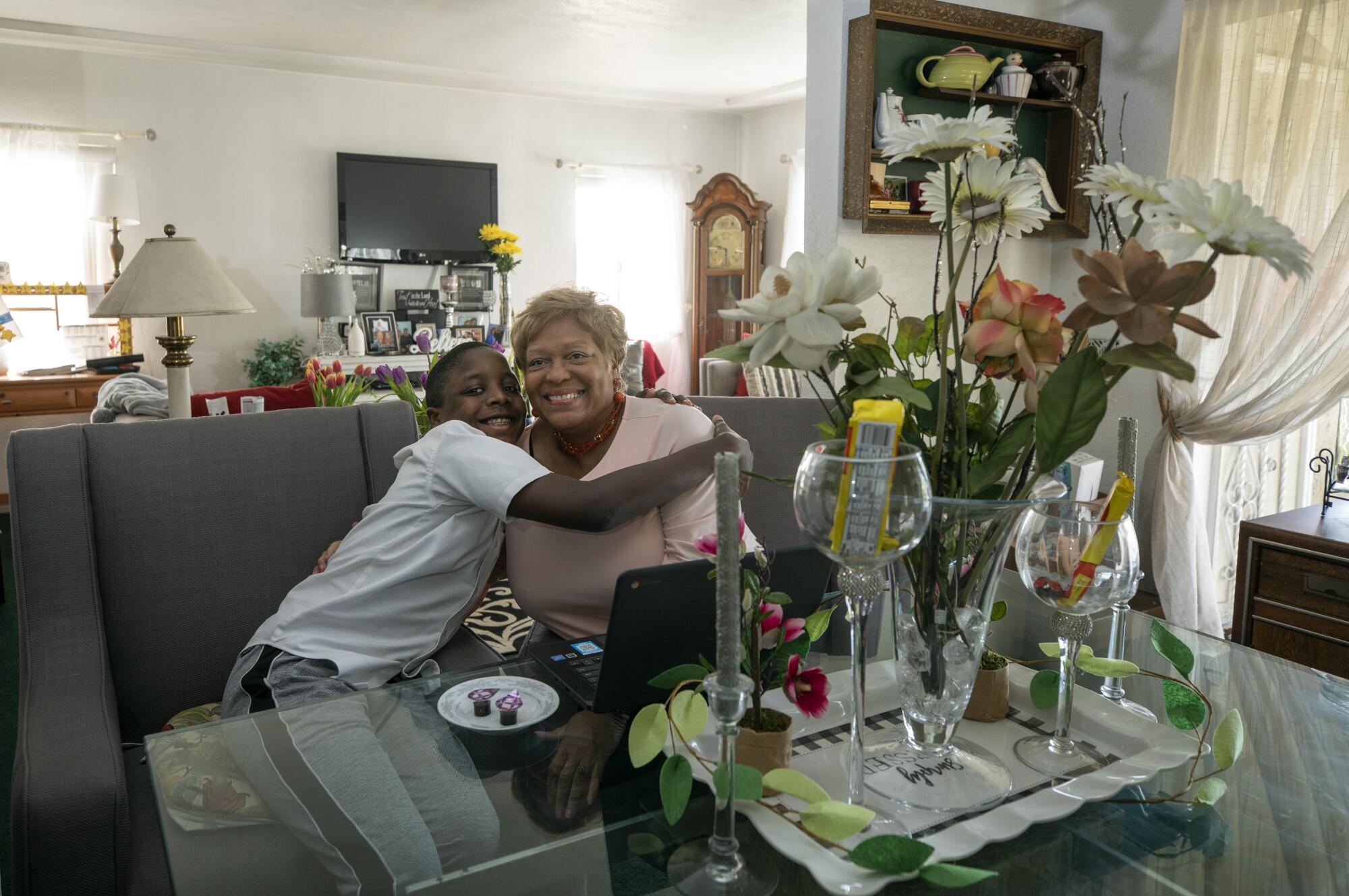 Denice Daye and her grandson Donte Murray sit in front of a laptop at her dining room table