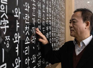 Kim Hyeong-bae, a senior researcher, inspects a relief sculpture of the book of the Korean alphabet in its original form displayed inside the institute.
