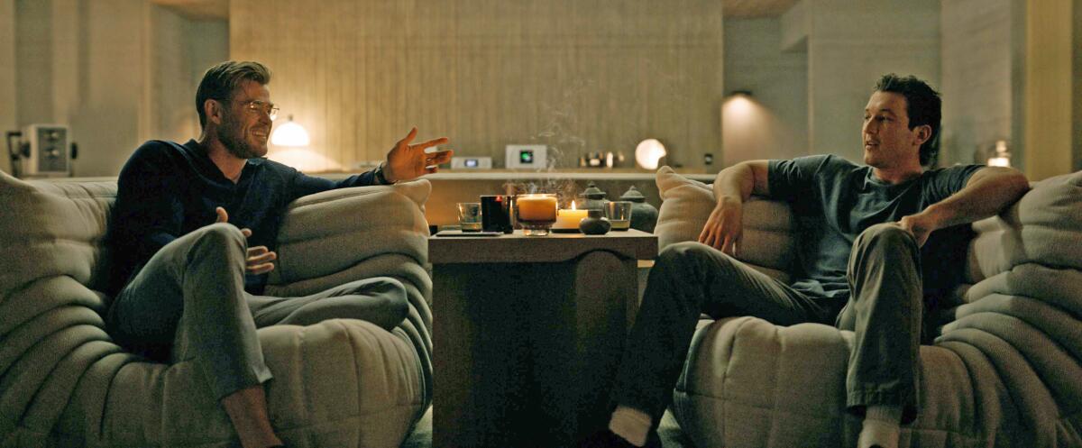 Two men chat in futuristic armchairs.