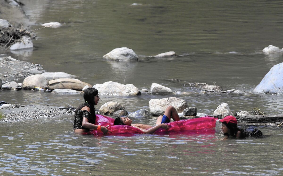 Children play in the east fork of the San Gabriel River during a heatwave.
