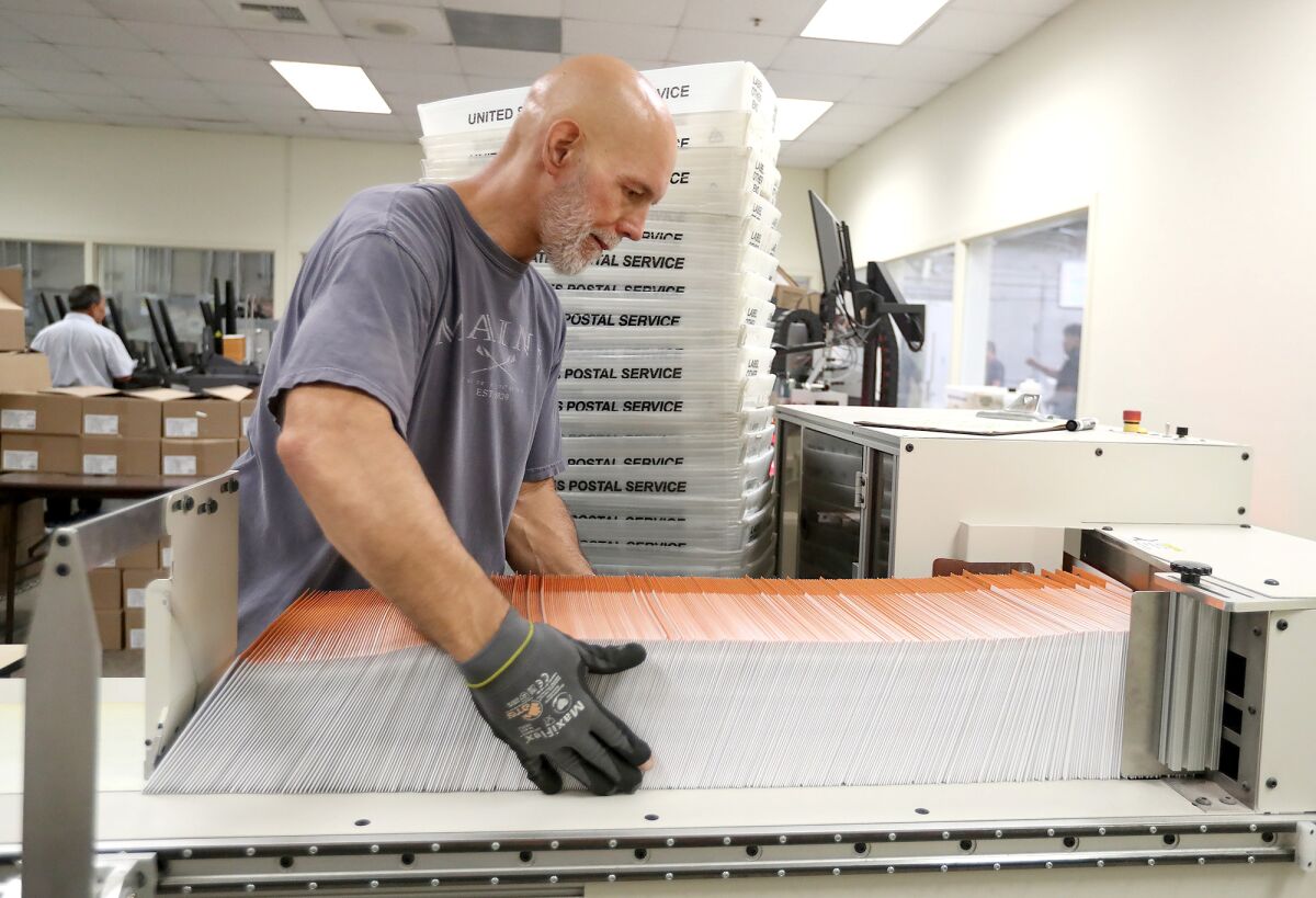 Employee John Rice boxes ready-to-send ballot envelopes at the county's Registrar of Voters facility in Santa Ana Wednesday.