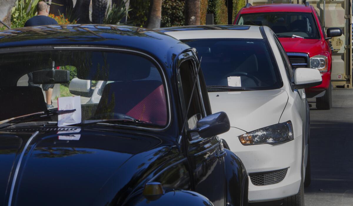 Parking tickets under windshield wipers on cars parked on the street