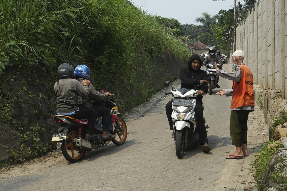 Husin bin Nisan, a volunteer traffic attendant, receives a tip from a motorist in Tangerang, Indonesia.