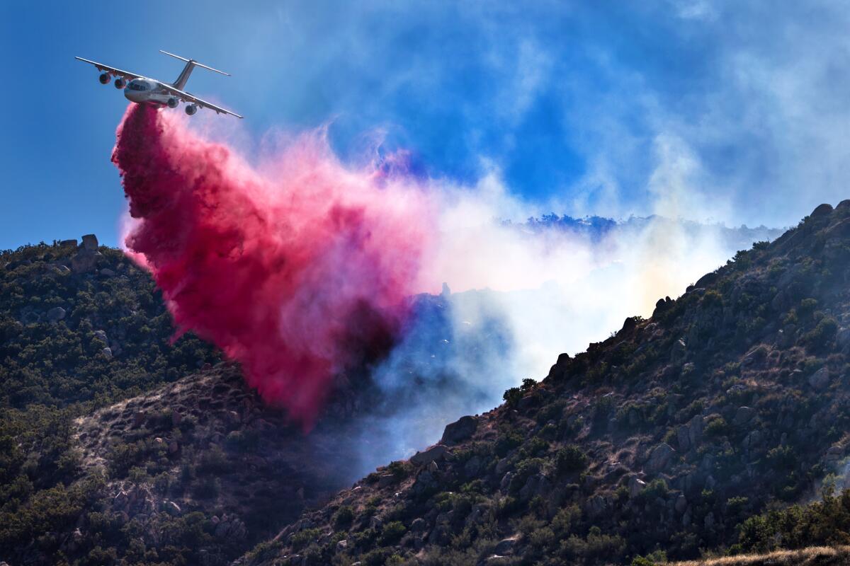 A firefighting plane drops retardant as the Highland fire burns along Highway 371 in Aguanga.