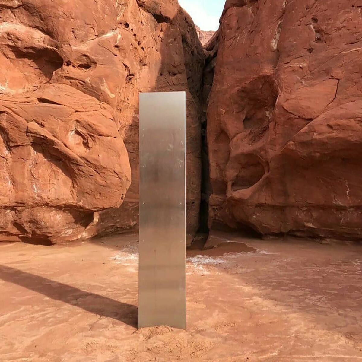 A metal monolith planted in the ground in a remote area of red rock in Utah.