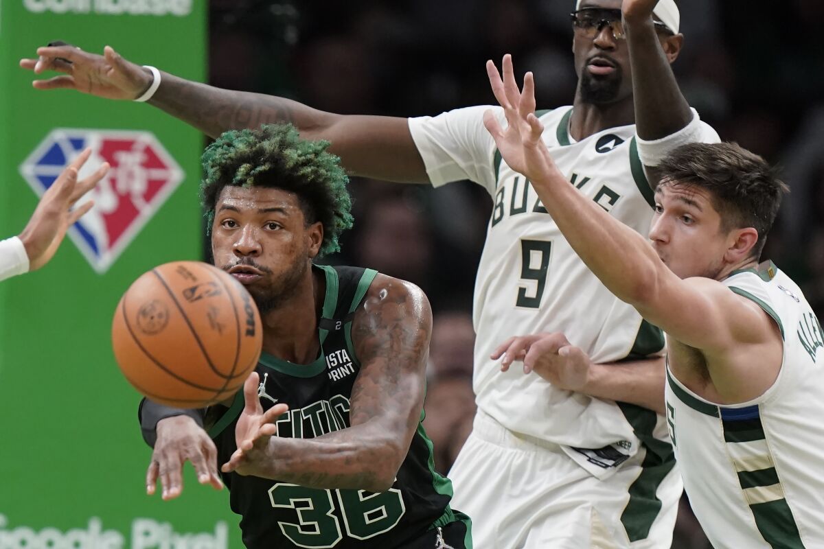 Boston Celtics guard Marcus Smart (36), left, passes the ball as Milwaukee Bucks center Bobby Portis (9) and guard Grayson Allen, right, try to defend the first half of Game 1 in the second round of the NBA Eastern Conference playoff series, Sunday, May 1, 2022, in Boston. (AP Photo/Steven Senne)