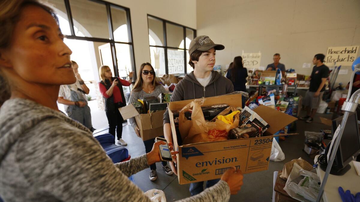 Grace Kastenberg, left, a volunteer with the Las Virgenes Fire Relief Center in Agoura Hills, directs donors Kelly Anderson and her 16-year-old son Matthew as they deliver items to the relief center.