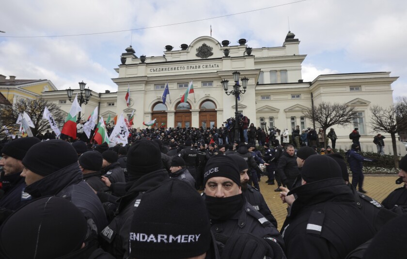 Police officers line up as they try to keep protesters away from the Bulgarian Parliament building in Sofia, Wednesday, Jan. 12, 2022. Protesters opposing COVID-19 restrictions in Bulgaria have clashed with police as they were trying to storm the Parliament in Sofia. Heavy police presence prevented protesters from entering the building and some were detained. (AP Photo/Valentina Petrova)