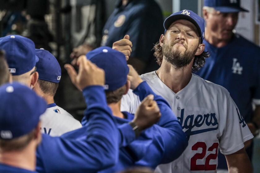 Dodgers pitcher Clayton Kershaw shows a look of satisfaction while greeting his teammates in the dugout.