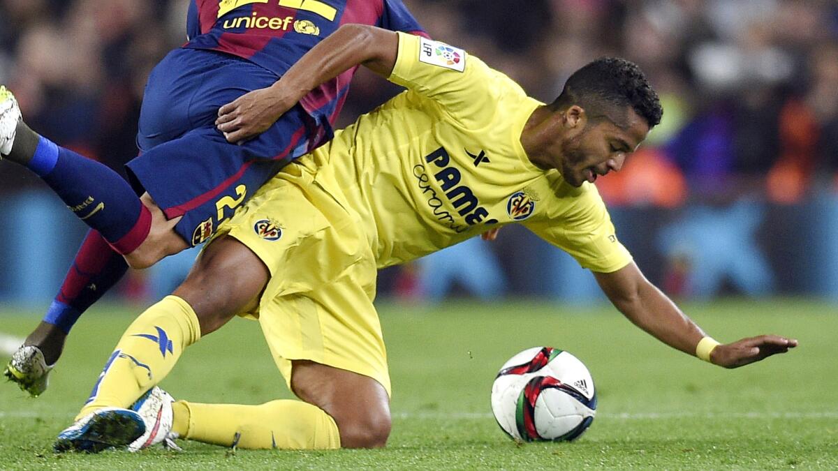 Villareal forward Giovani Dos Santos, right, battles Barcelona defender Dani Alves for the ball during a Spanish Copa del Rey semifinal match in Barcelona on Feb. 11. Dos Santos has played his entire professional career outside of his native Mexico.