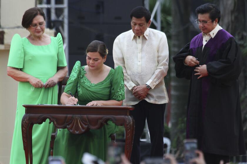 Sara Duterte, daughter of outgoing populist president of the Philippines, signs documents during her oath taking as vice president in her hometown in Davao city, southern Philippines, Sunday, June 19, 2022. Duterte clinched a landslide electoral victory despite her father's human rights record that saw thousands of drug suspects gunned down. Also in photo are, from left, her mother Elizabeth Zimmerman, Philippine President Rodrigo Duterte and Supreme Court Justice Ramon Paul Hernando. (AP Photo/Manman Dejeto)