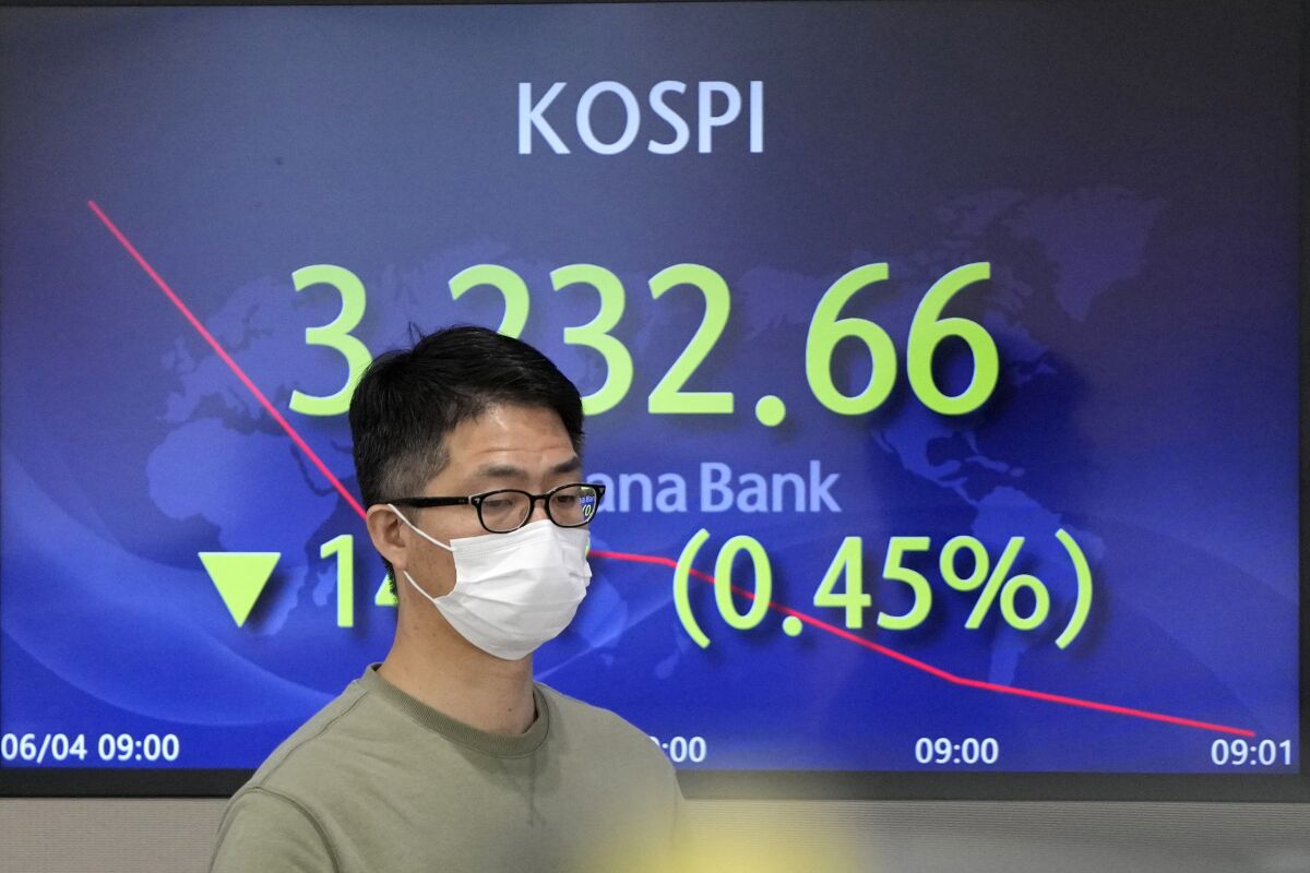 A currency trader walks by the screen showing the Korea Composite Stock Price Index (KOSPI) at the foreign exchange dealing room in Seoul, South Korea, Friday, June 4, 2021. Asian shares mostly slipped Friday, dragged lower by a decline in technology stocks on Wall Street.(AP Photo/Lee Jin-man)