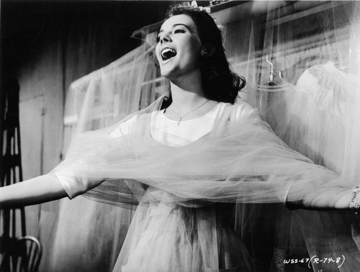 A young woman sings while wrapped in tulle fabric.